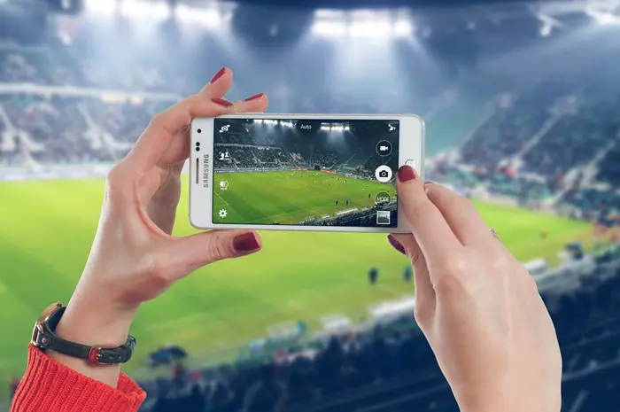 Egy h�lgy egy stadionban telefonnal fot�t k�sz�t